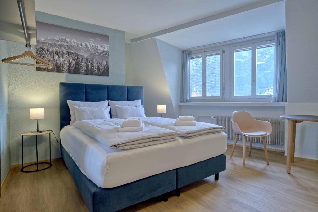 Un dormitorio con una cama grande y dos ventanas. en BANK House Studio M 405 - GRIWA RENT, en Interlaken