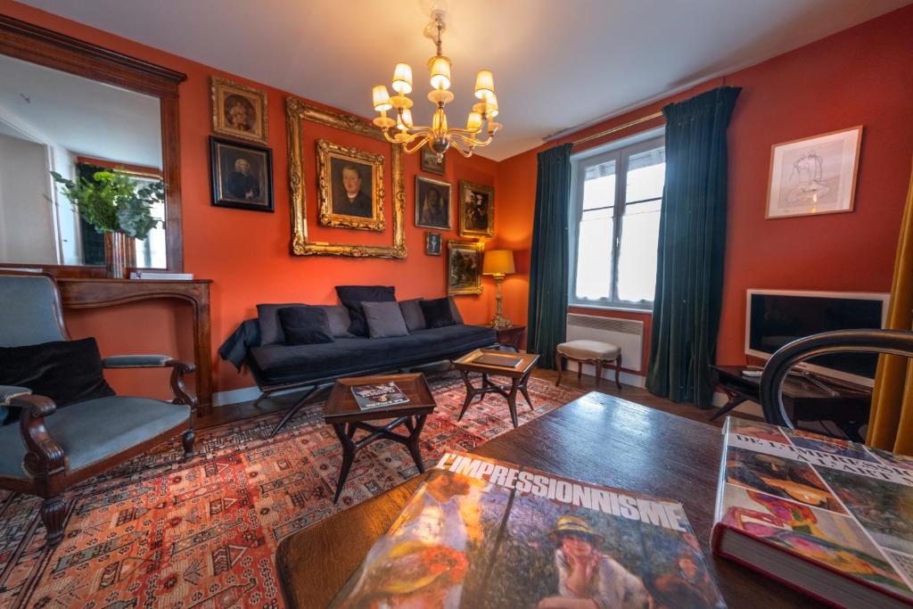 d'un salon avec des murs orange et un lustre. dans l'établissement Centre historique de LYONS LA FORET Hotel de Maître le Cottage, à Lyons-la-Forêt