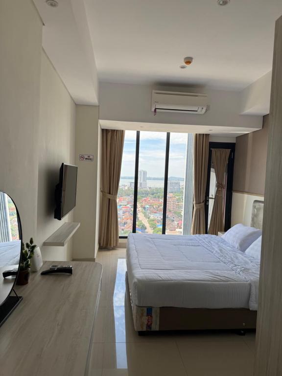 a hotel room with a bed and a large window at Pollux Habibie Deluxe Sea View By Superstay in Batam Center