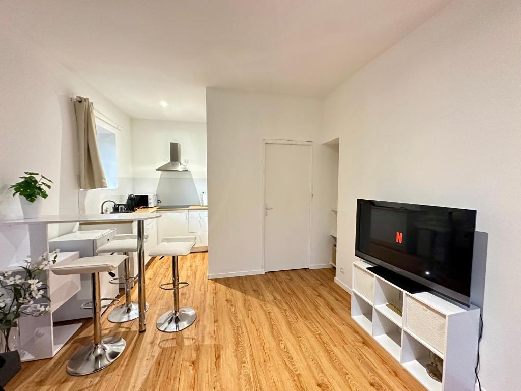 un salon avec une télévision, une table et des chaises dans l'établissement Studio cosy face à l'église, à Le Mas-dʼAgenais