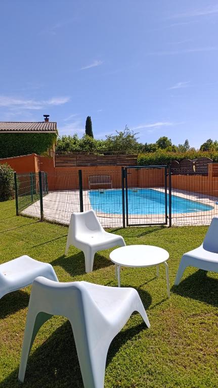 - un groupe de chaises et de tables blanches en face d'une piscine dans l'établissement Mas de la Grave, à Althen-des-Paluds