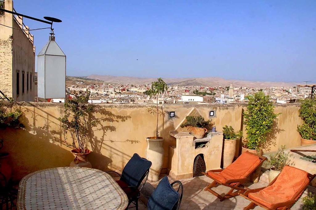 a patio with chairs and a table and a view of a city at Charming Riad Medina View 4 AC Bedrooms Panoramic Terrace Central Fez in Fès al Bali