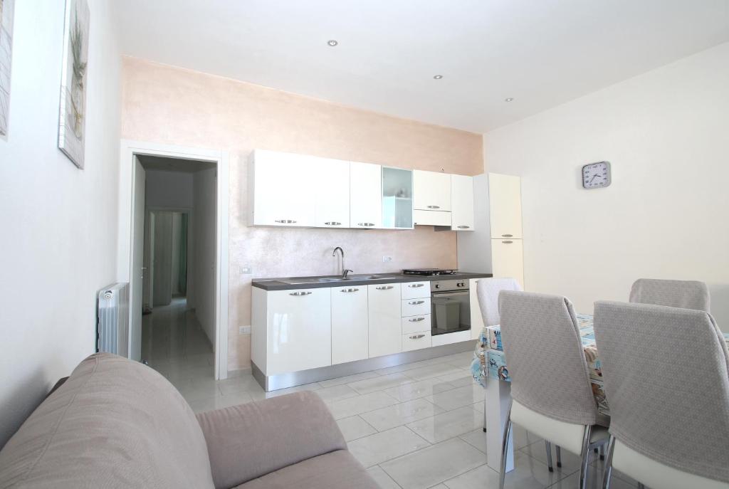 a kitchen with white cabinets and a table and chairs at Palau Fonte Vecchia Apartment in Palau