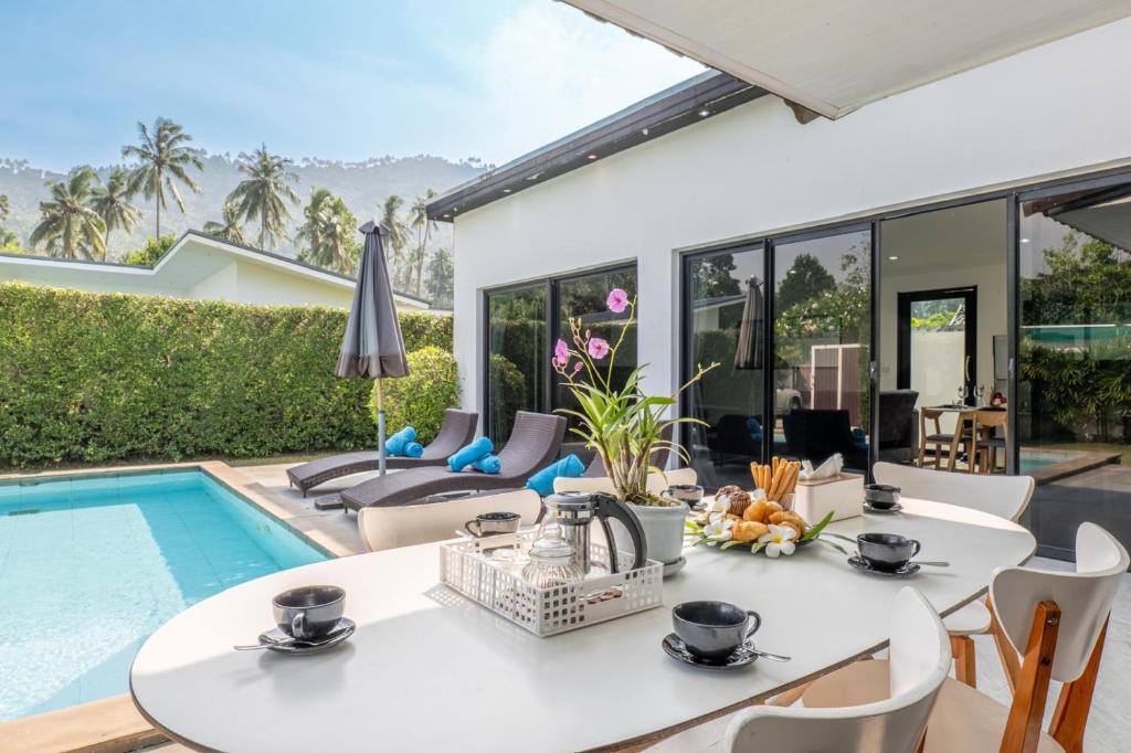 a dining room with a table and chairs and a swimming pool at Villas Eden in Lamai