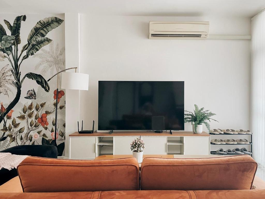 een woonkamer met een bank en een flatscreen-tv bij Casa Palm Spring in Bangkok