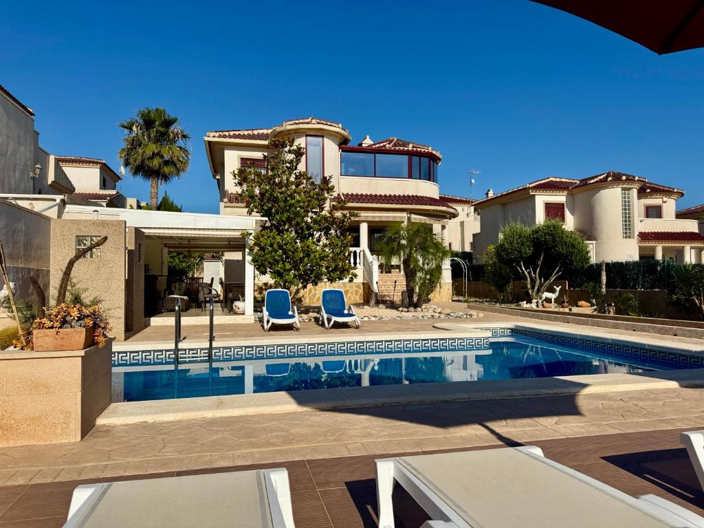 a villa with a swimming pool and two blue chairs at Maikran Premium Fantastic Family Villa with Pool in San Fulgencio