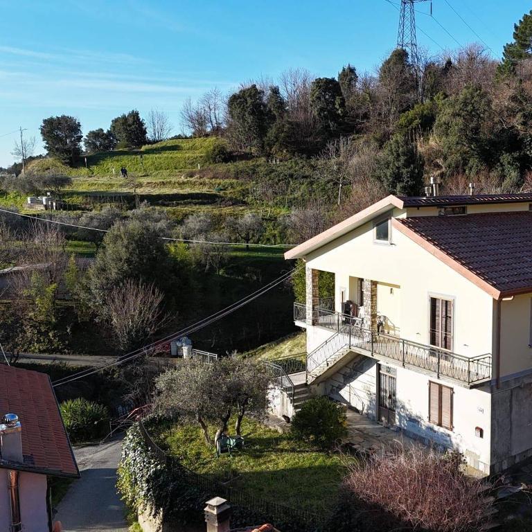 a white house with a balcony next to a river at Appartamento Il Salice in Carignano