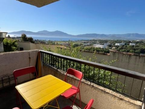 une table et des chaises jaunes sur un balcon avec vue dans l'établissement Charmant 2 pièces avec vue sur mer exceptionnelle à Porticcio, Corse du Sud, à Grosseto-Prugna