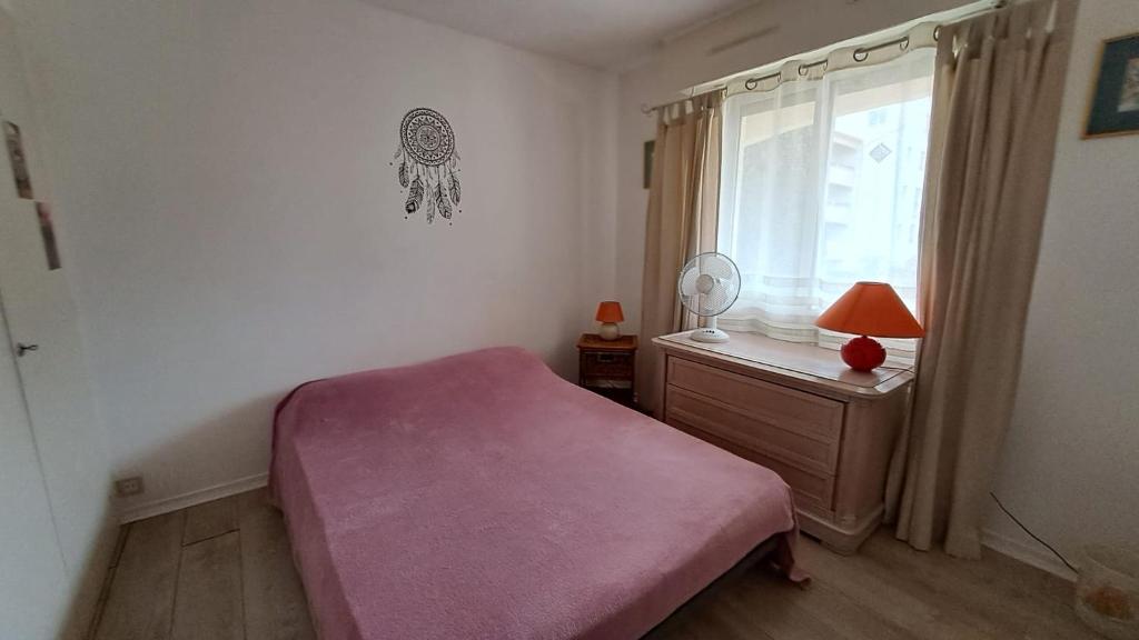 - une chambre avec un lit rose et une fenêtre dans l'établissement Appartement calme et idéalement situé, à Fréjus