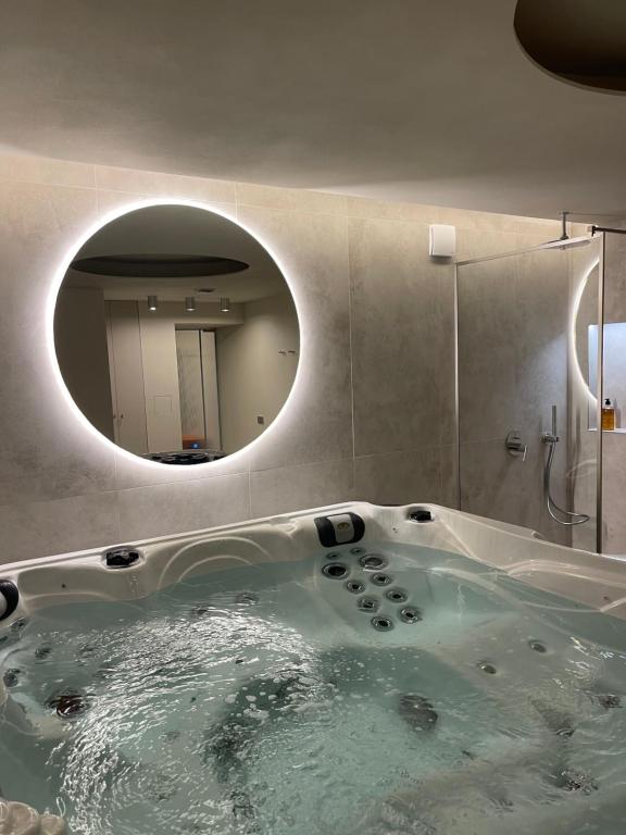 梅尔尼拉杰APARTAMENTAI SPA MORENA Klaipėda的带浴缸和圆镜子的浴室