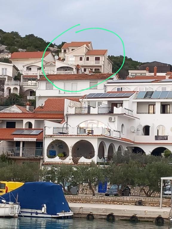 a large white building with a blue tent next to the water at Apartmani Frkic in Tisno