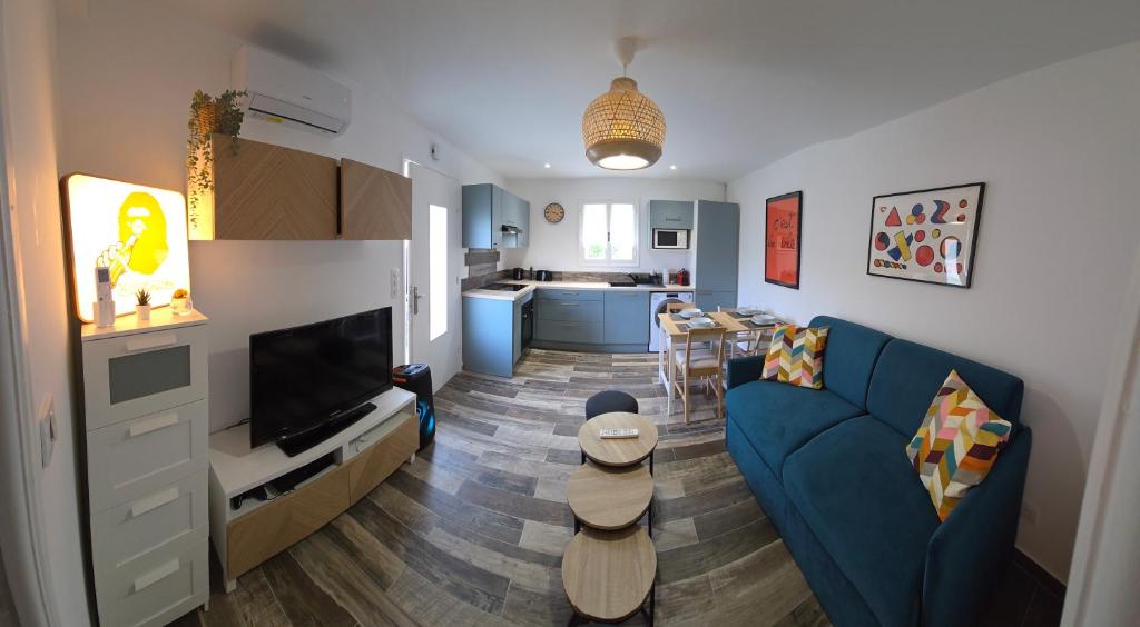 un salon avec un canapé bleu et une cuisine dans l'établissement T2 rez de jardin de villa au calme, à Nice