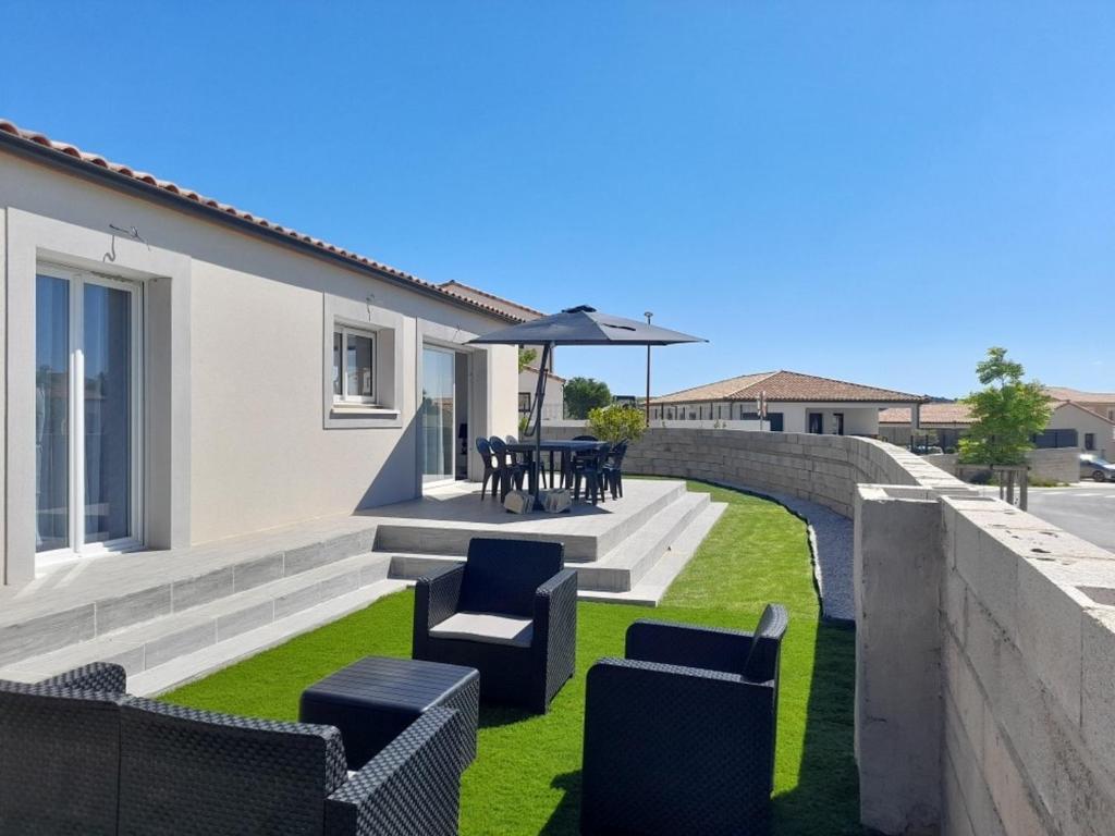 un patio avec des chaises, une table et un parasol dans l'établissement La Villa les Terrasses du Canal, à Capestang