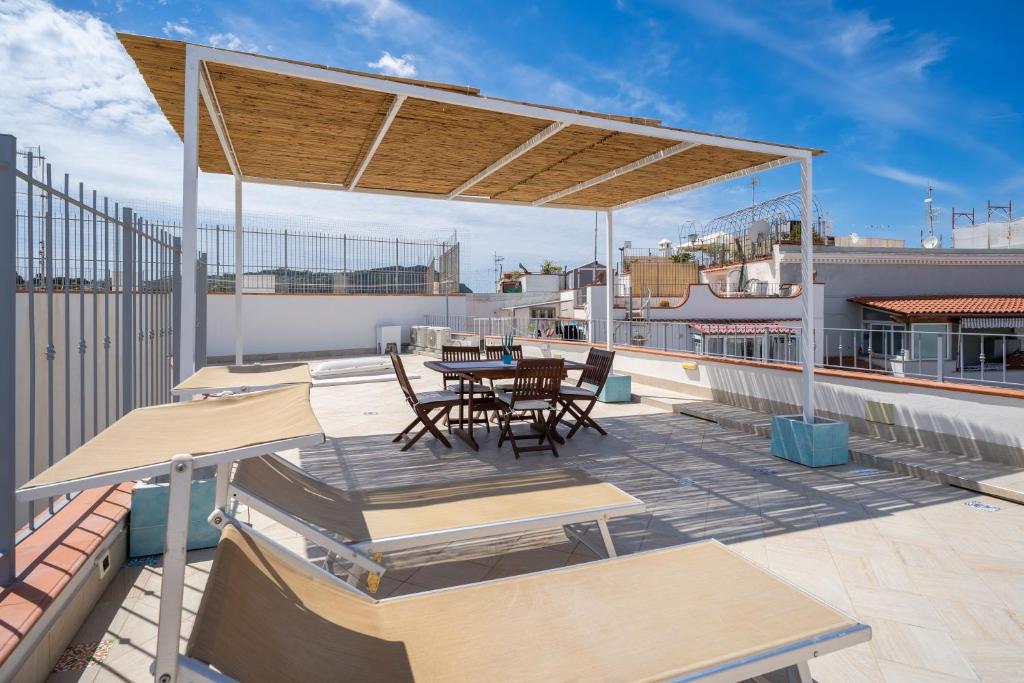 un patio avec une table et des chaises sur un toit dans l'établissement 2 Terraces and Pergola House in Ischia, à Ischia