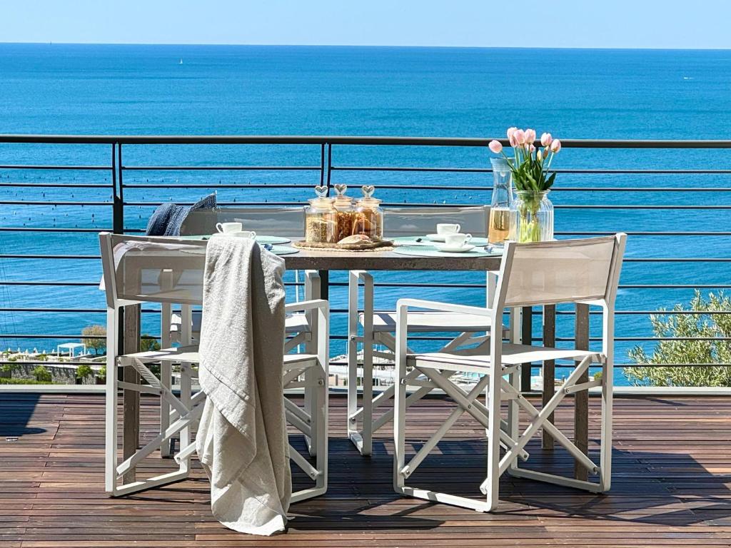 a table and chairs on a deck with the ocean at Portopiccolo Apartments - Ulivo sul golfo in Portopiccolo Sistiana