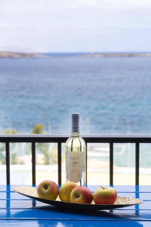 a bottle of wine and some apples on a table at Seafront living with private Garage in St. Paul's Bay
