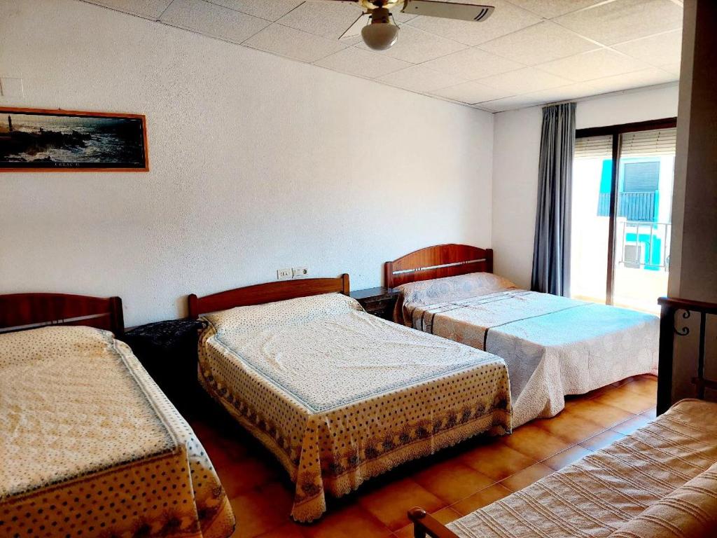 a room with three beds and a window at Spacious casa con 3 dormitorios para 9 personas y en primera línea del mar in Oropesa del Mar