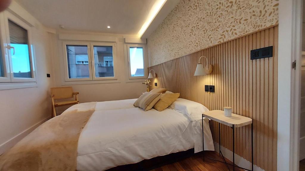 a bedroom with a large white bed and two windows at Apartamento Atlantico Pontus Veteris in Pontevedra