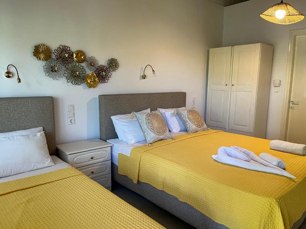two beds in a bedroom with yellow sheets at Maniatis Garden in Achladies