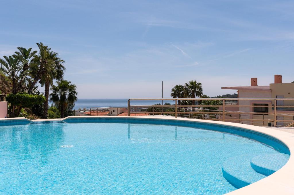 セジンブラにあるBmyGuest - Sesimbra Palames Beach & Pool Apartmentの海を背景にした大型スイミングプール