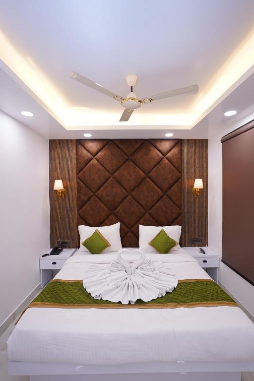 ein Schlafzimmer mit einem großen weißen Bett mit einem hölzernen Kopfteil in der Unterkunft Sara Fortune International in Noida