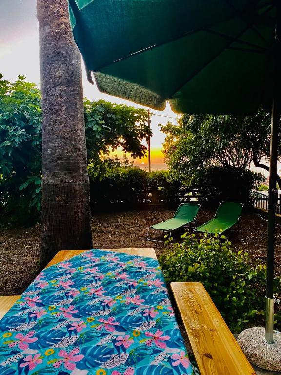 a table with an umbrella and two chairs and a rug at Apartment in Villa under Grand Palm Tree & Garden in Porto Alabe