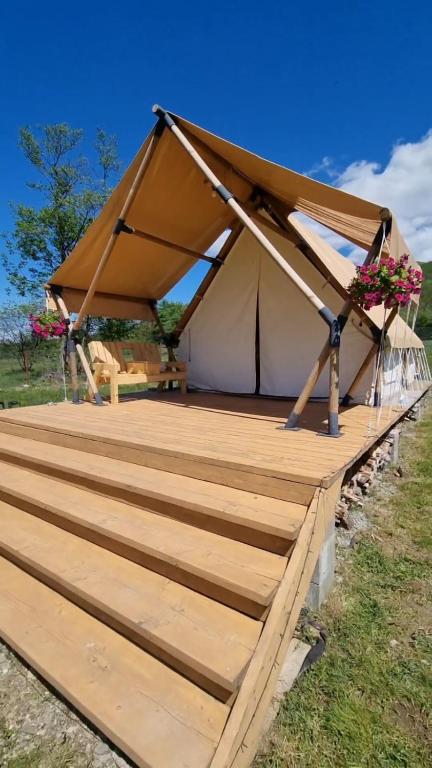 a tent with a wooden deck in a field at Veselia Glamping in Valea Drăganului
