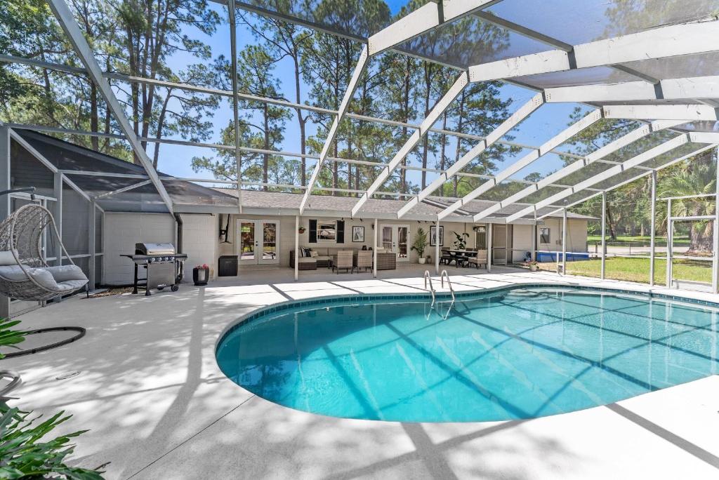 an indoor swimming pool with a pergola and a house at Designer Pet-Friendly Retreat with Heated Pool home in Ocala
