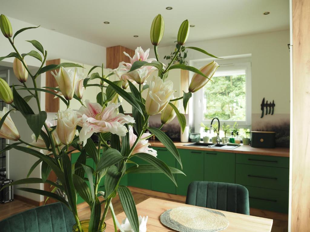 a kitchen with a table with a vase of flowers at Apartament ZIELONO MI 2 in Jedlina-Zdrój