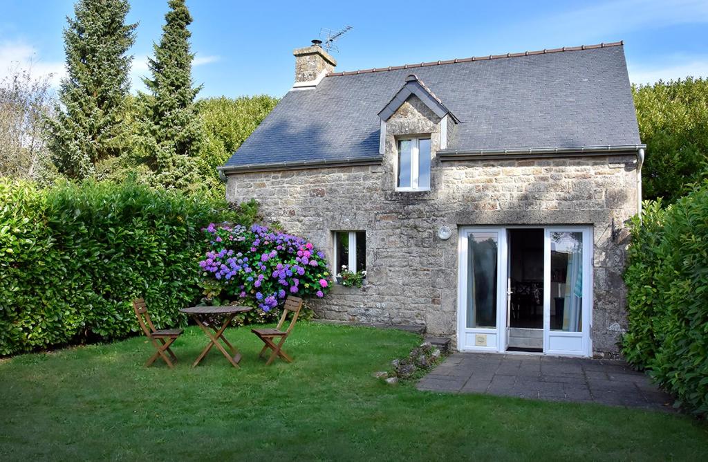 une maison en pierre avec une table de pique-nique et des fleurs dans l'établissement Charmante maison bretonne, à Séglien