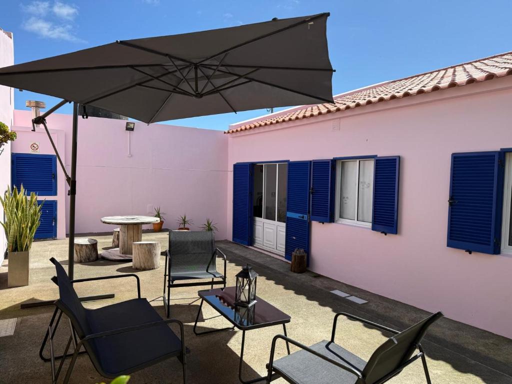 a patio with chairs and a table and an umbrella at Baleeiro do Cais:Harbour House, Fishing, Fireplace in Ponta Delgada
