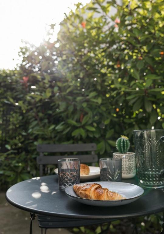 une table avec une assiette de pain et des verres dans l'établissement Terrasse, Soleil et Confort - Studio Neuf à Montpellier, à Montpellier