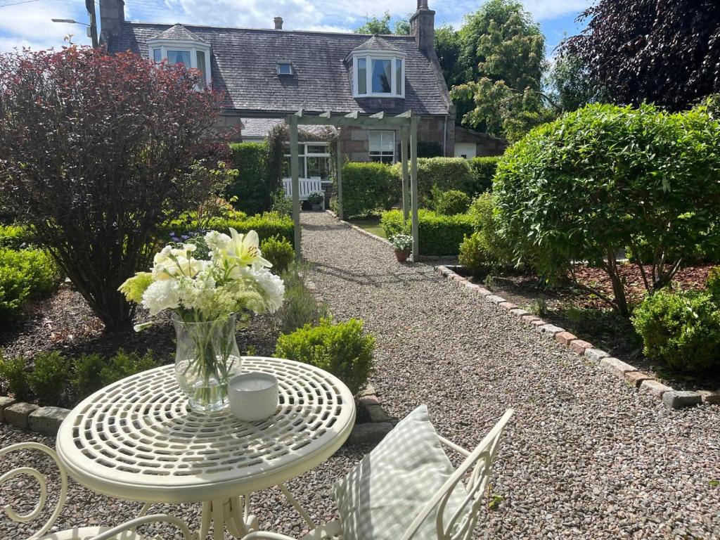 a table with a vase of flowers on top of it at Craigen Cottage Ballater in Ballater