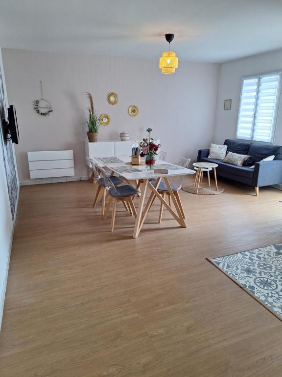a living room with a table and chairs and a couch at Chez Léonie in Sainte-Mère-Église