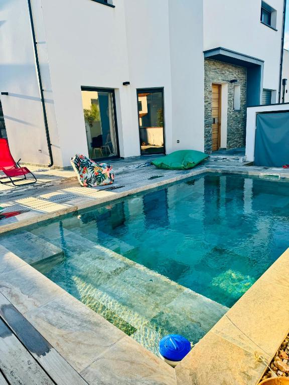 une piscine avec de l'eau bleue dans un immeuble dans l'établissement Maison LUMIERE, à Saleilles