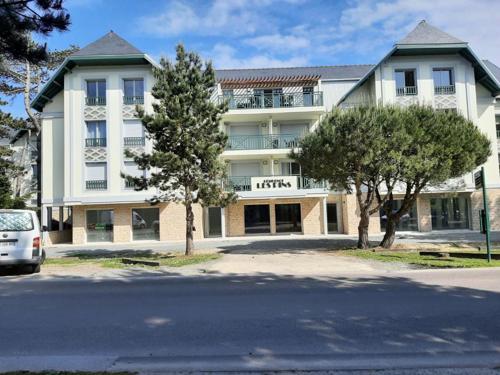 un grand bâtiment blanc avec des arbres devant lui dans l'établissement Les Sables d'or, à Fréhel