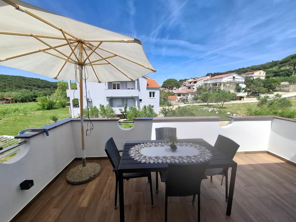 a table and chairs on a balcony with an umbrella at Marija šimičić in Rab