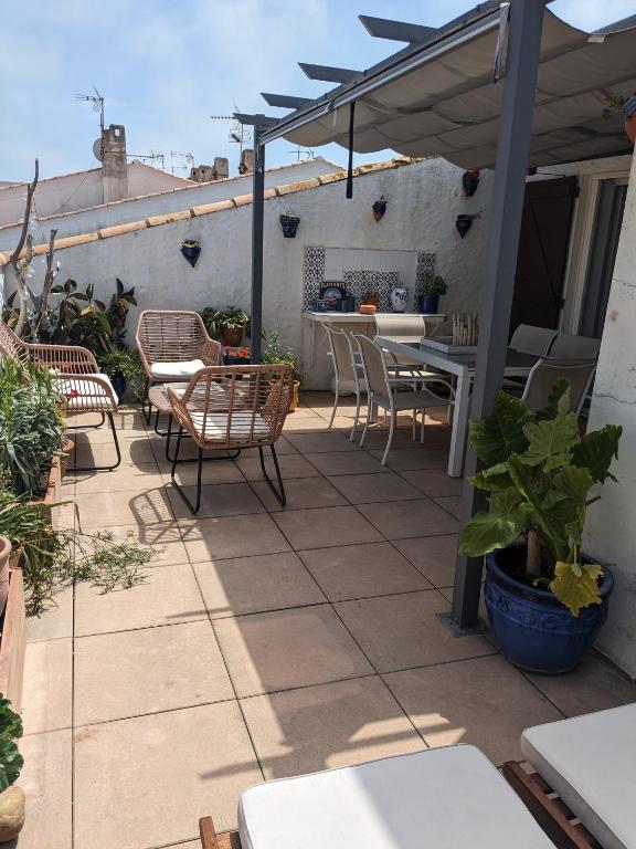 a patio with a table and chairs and an umbrella at Appartement climatisé toit terrasse à la mer in Saintes-Maries-de-la-Mer