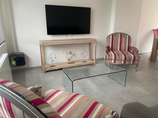 un soggiorno con TV e 2 sedie di La maison de Julien a Bourbourg