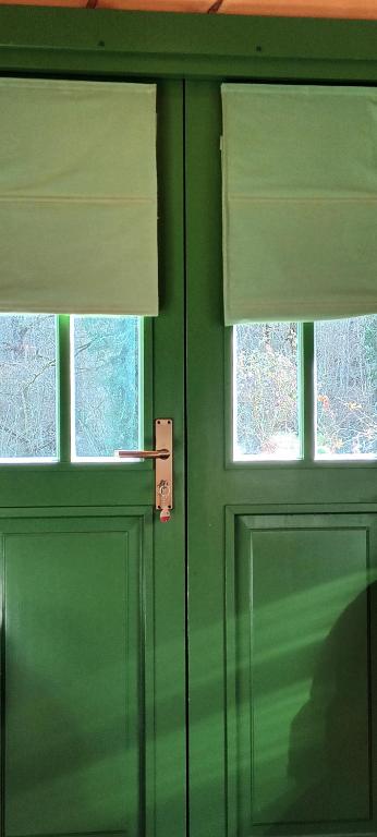 une porte verte avec deux fenêtres dans une pièce dans l'établissement La Roulotte 4pl confort Au bord de la Rivière, à Laguépie