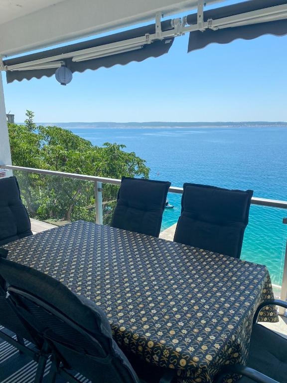 a table and chairs on a balcony with the ocean at Beach Apartments Luka in Tribanj-Krušćica