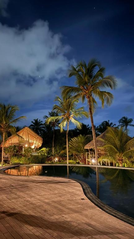 a resort with palm trees and a pool at night at Villa Sabiá - Eco Bungalows in Prea