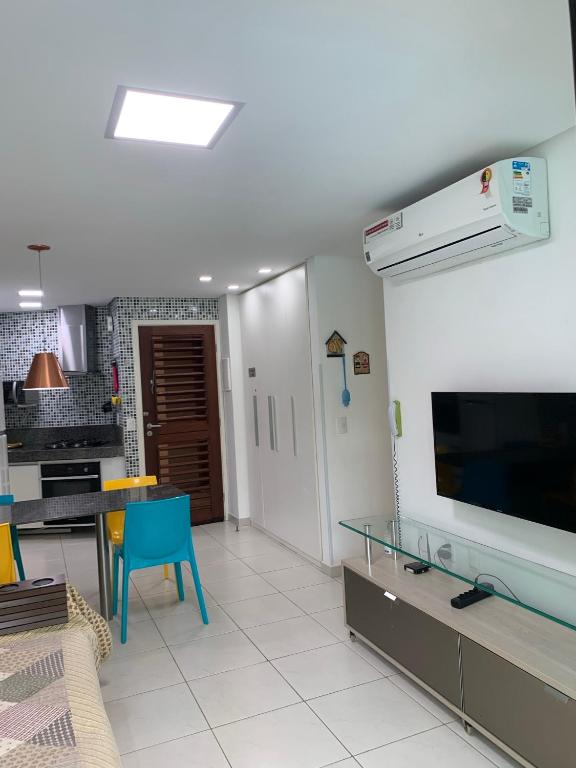 a living room with a flat screen tv and a table at Carneiros Beach Resort Flat in Tamandaré