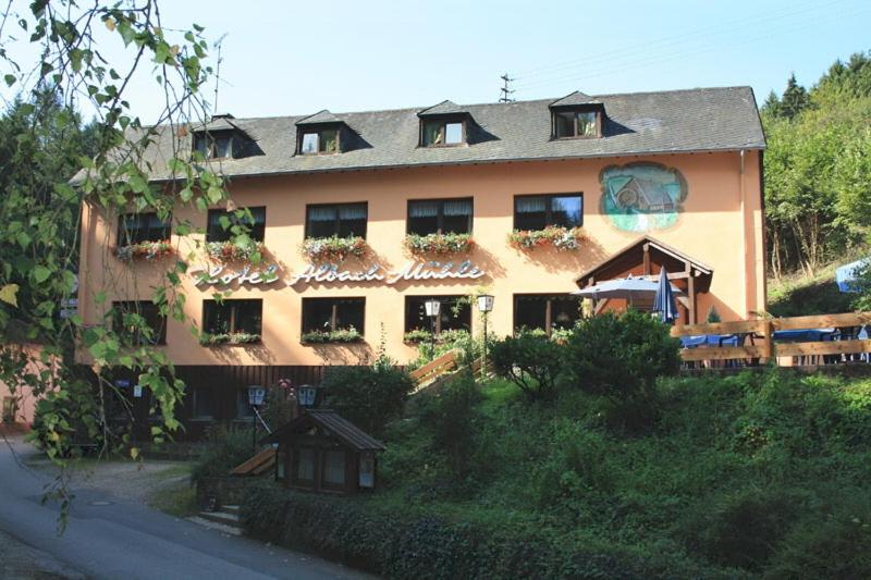 a large building with plants on the windows of it at Waldhotel Albachmühle mit Albacher Stuben in Wasserliesch