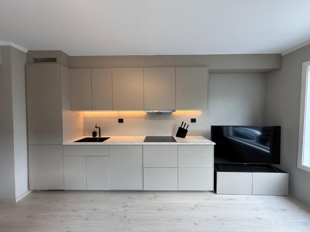 a white kitchen with a sink and a microwave at Moderne hus i sentrum av Lillestrøm in Lillestrøm