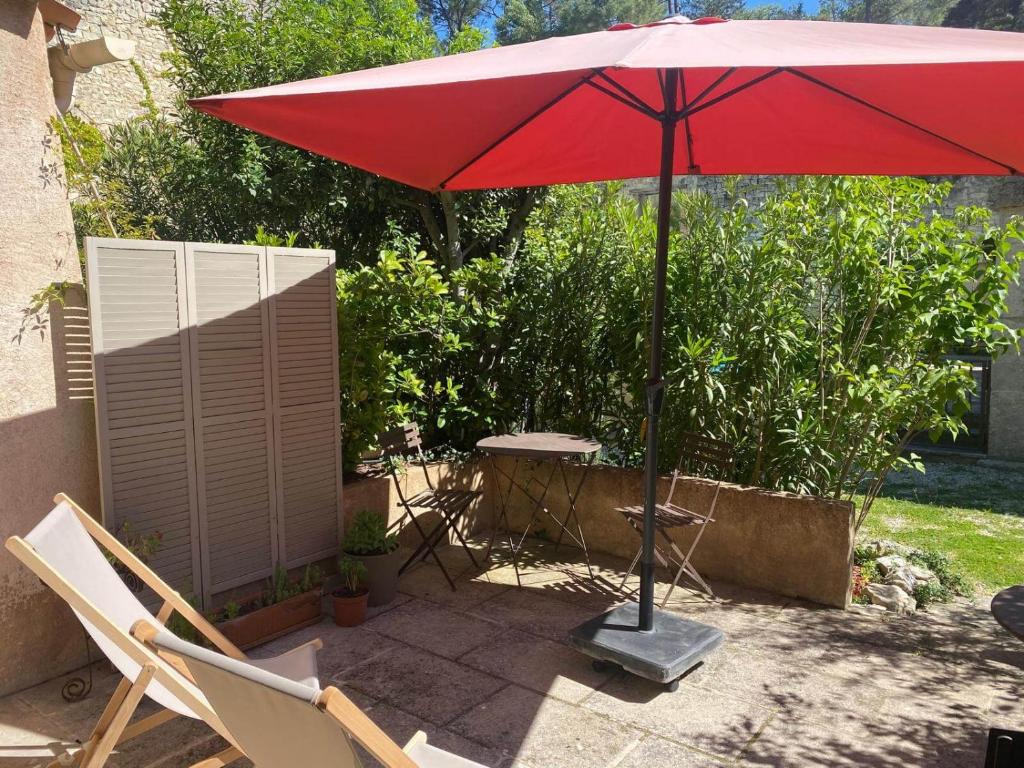 un parasol rouge, deux chaises et une table dans l'établissement Séjour au pied du colorado provençal, avec piscine, à Rustrel
