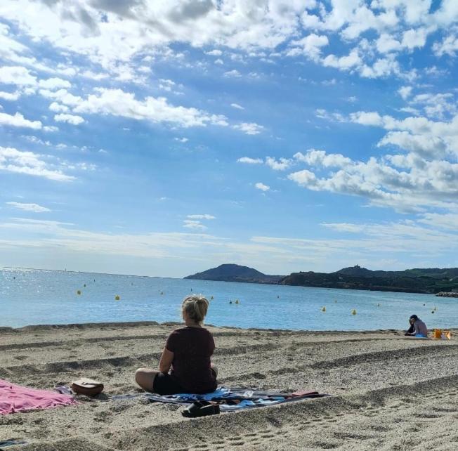 une femme assise sur la plage en regardant l'eau dans l'établissement Résidence Plein Sud, à Argelès-sur-Mer
