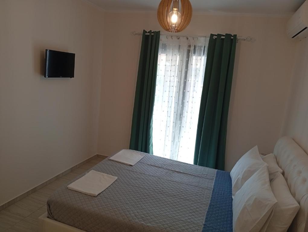 a bedroom with a bed and a window with green curtains at LV apartment-in the heart of Parga in Parga