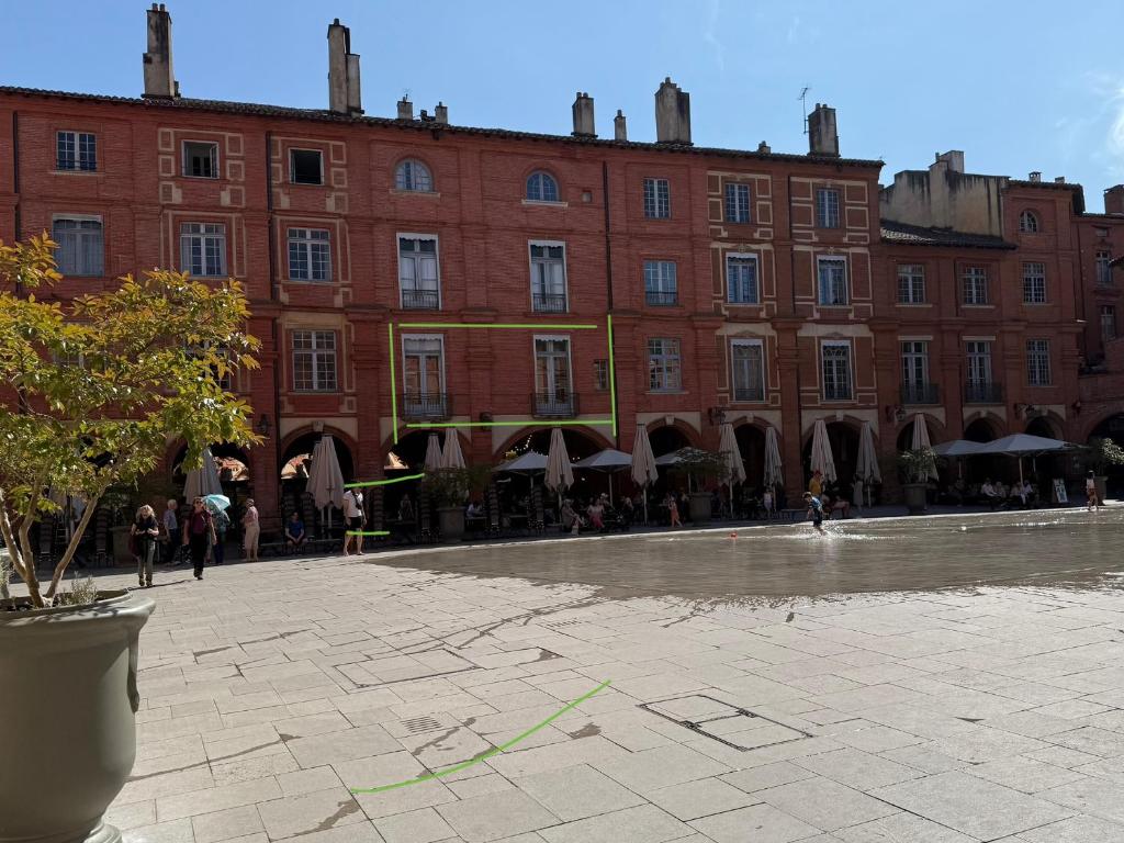 un grand bâtiment en briques avec une cour en face dans l'établissement La réserve des drapiers, à Montauban