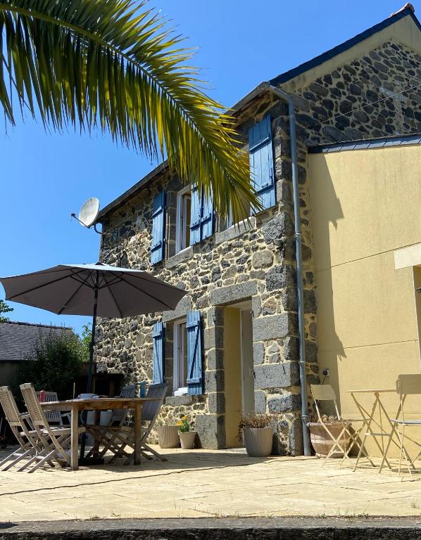 une maison avec une table et un parasol devant elle dans l'établissement Maison chaleureuse toute équipée pour vos vacances, à Saint-Quay-Portrieux